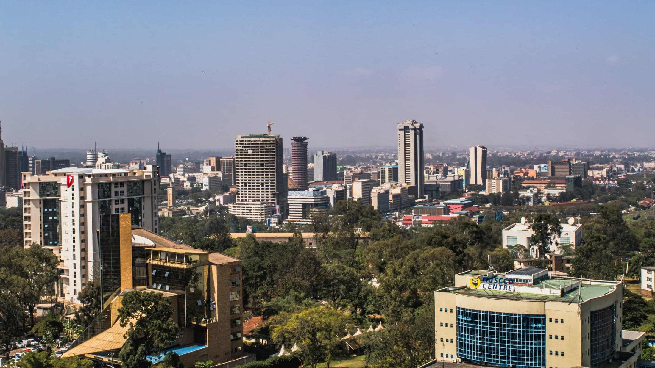 Elevated view across Nairobi with mid-rise buildings and tree cover