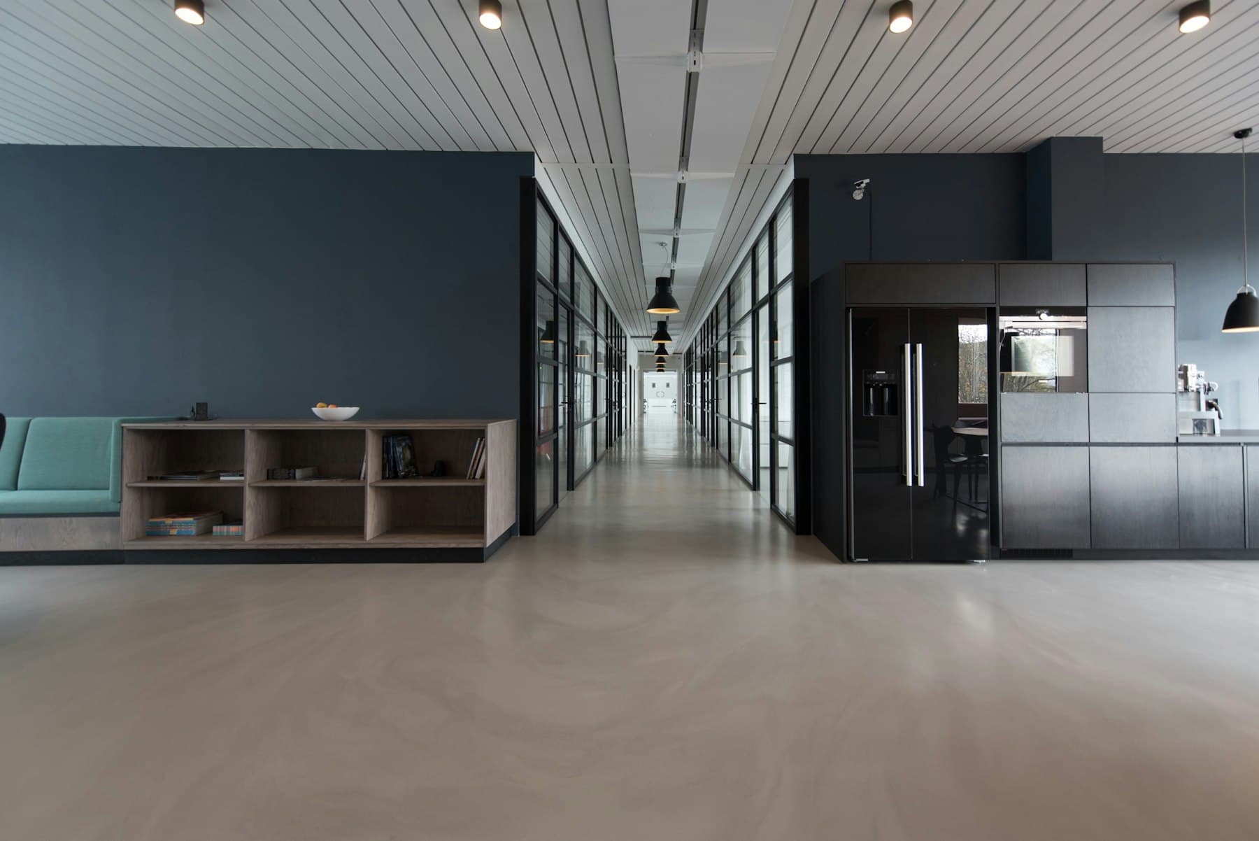 A bright, quiet office corridor with glass-walled rooms
