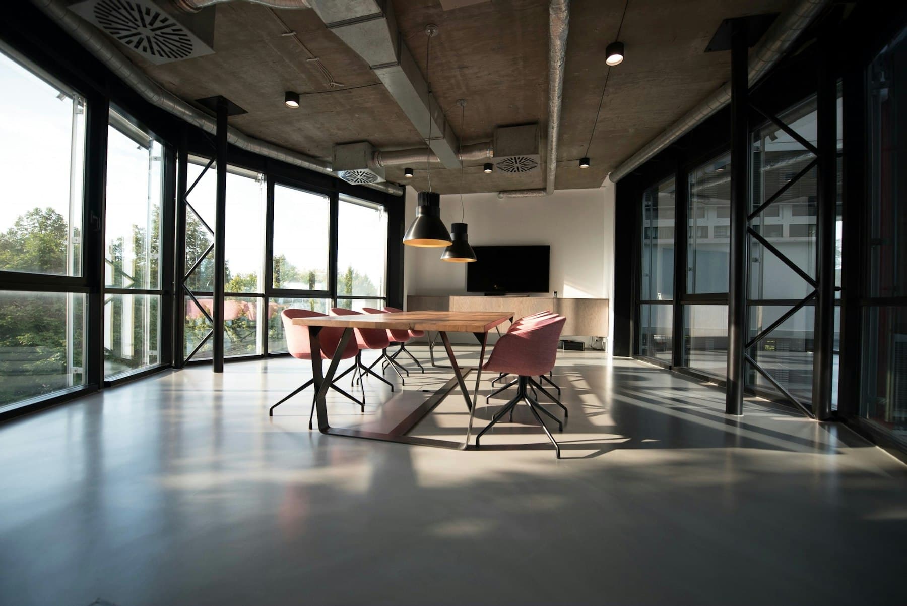 Open-plan office with floor-to-ceiling glass and a long meeting table